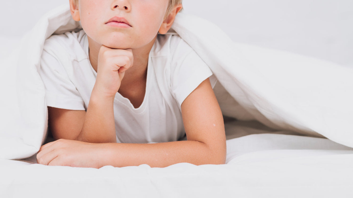 Infante acostado bajo una sábana, asociado a la apnea del sueño en niños.
