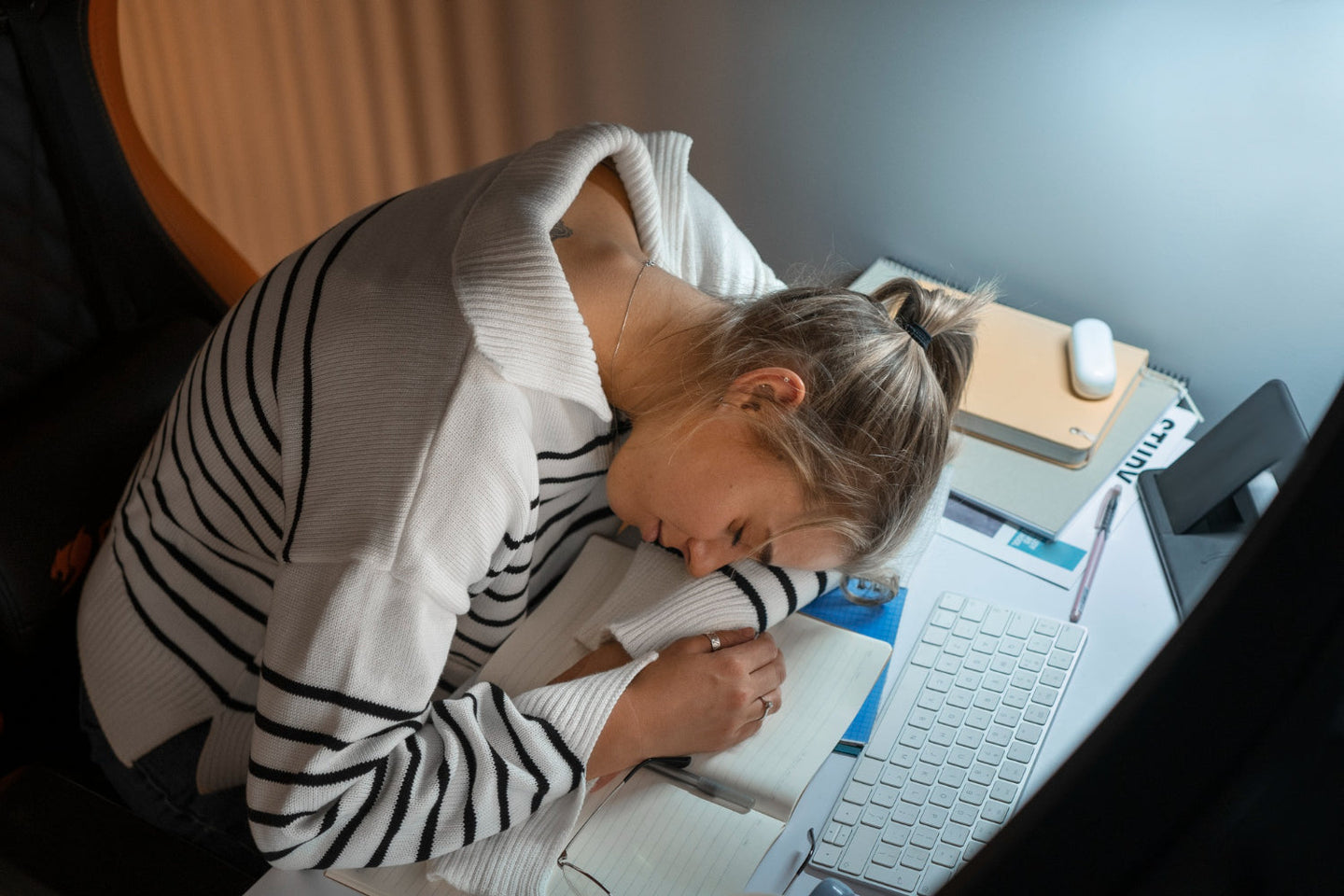 Mujer dormida en el escritorio, mostrando qué es la hipersomnia.