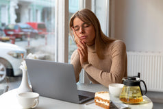 Mujer con somnolencia postprandial se queda dormida frente a su laptop tras comer, reflejando cómo afecta la rutina diaria.