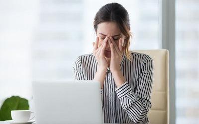Mujer frente a su computadora con expresión de agotamiento, preguntándose por qué me levanto cansada y sin energía.