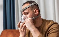 Hombre colocándose una mascarilla CPAP, reflejando el proceso de adaptación inicial y posibles molestias del tratamiento para apnea del sueño.