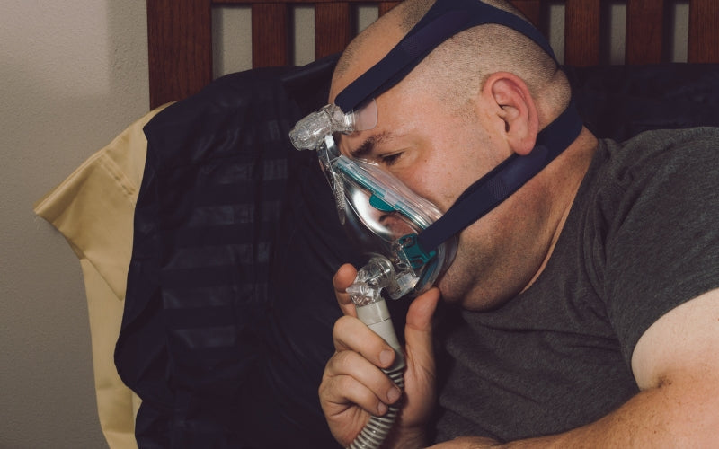 Hombre usando mascarilla CPAP para tratar la apnea del sueño y aplicar estrategias que le ayudan a evitar la claustrofobia y descansar mejor