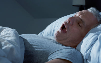 Hombre roncando intensamente bocarriba durante la noche, posible señal de apnea del sueño.